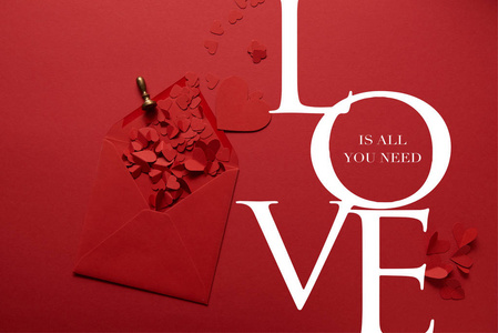 顶部的剪纸心和打开信封的红色背景与爱是你所需要的的字体