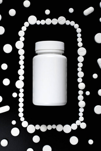 白色药丸，片剂和黑色背景上的白色瓶子。文本复制空间