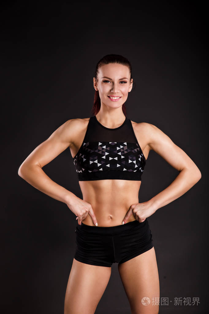 强壮的女性健美运动员与完美的腹肌, 肩膀, 二头肌, 三头肌和胸部.