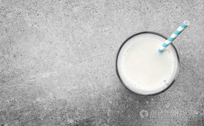 一杯新鲜牛奶，在混凝土背景上用吸管喝。 纯牛奶豆浆或牛奶和复制空间。
