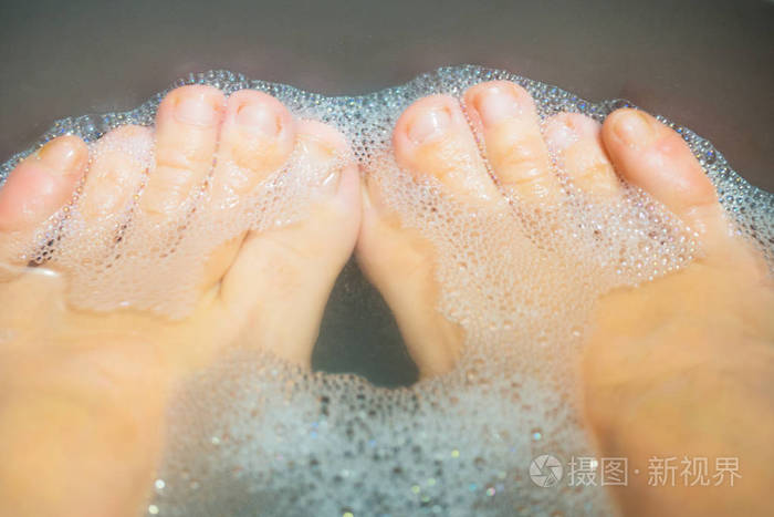 一盆泡沫里的脏脚. 脚趾靠近. 水疗放松
