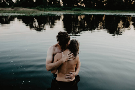 在湖里拥抱的年轻夫妇