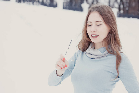 快乐和微笑的女孩在下雪时保持街道上的孟加拉灯。 冬季概念。 新年概念。