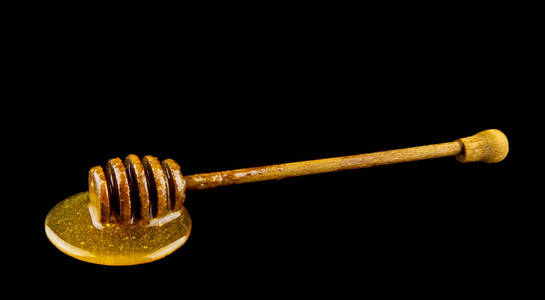 黑色背景的木勺上的蜂蜜