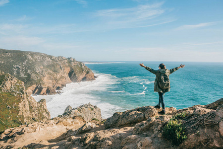 葡萄牙大西洋附近背着背包的徒步女孩举起双手, 显示出她是多么高兴