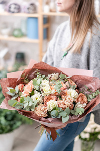 美丽的新鲜切花混合鲜花在女人的手。花店的花商的作品。精致的柔和色调颜色