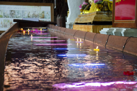 仪式祈祷五颜六色的蜡烛漂浮在水上，为祈祷，躺着佛陀的形象，在瓦特法拉，非查克拉西，瓦拉维汉寺庙，在辛格伯里市，泰国。