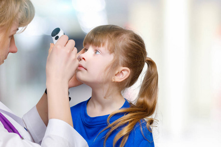 一位女眼科医生在医院房间背景下用特殊设备检查小儿童眼睛的特写。 眼睛问题治疗的概念。
