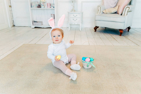 复活节戴着兔子耳朵玩彩蛋的小女孩