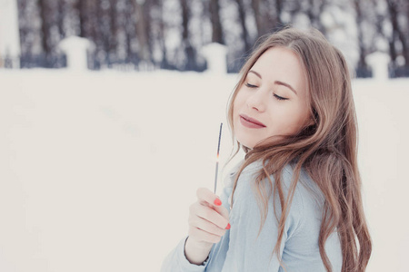 快乐和微笑的女孩在下雪时保持街道上的孟加拉灯。 冬季概念。 新年概念。