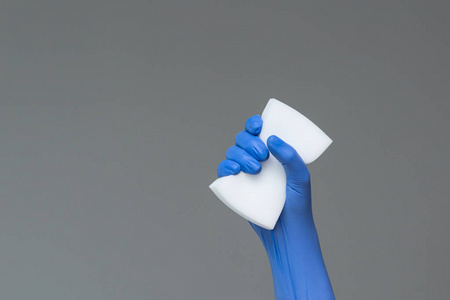 手中的橡胶手套，在中性背景上保持洗涤海绵。 明泉弹簧清洗的概念。