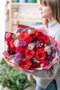 美丽的新鲜切花混合鲜花在女人的手。花店的花商的作品。红色