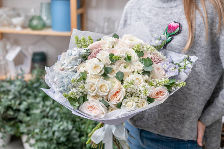 美丽的新鲜切花混合鲜花在女人的手。花店的花商的作品。精致的柔和色调颜色