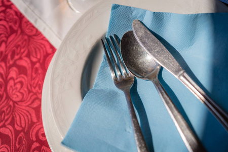 在餐厅开始服务之前，在桌子上的盘子上用叉子刀和勺子在蓝色餐巾纸上