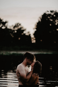 在湖里拥抱的年轻夫妇