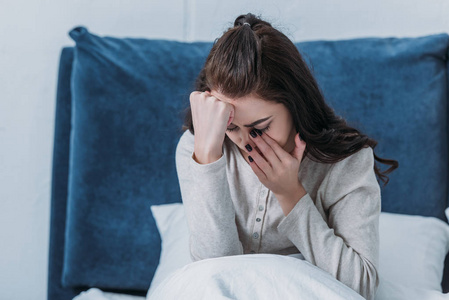 擦眼泪沮丧的女人在家里躺在床上哭着擦眼泪照片