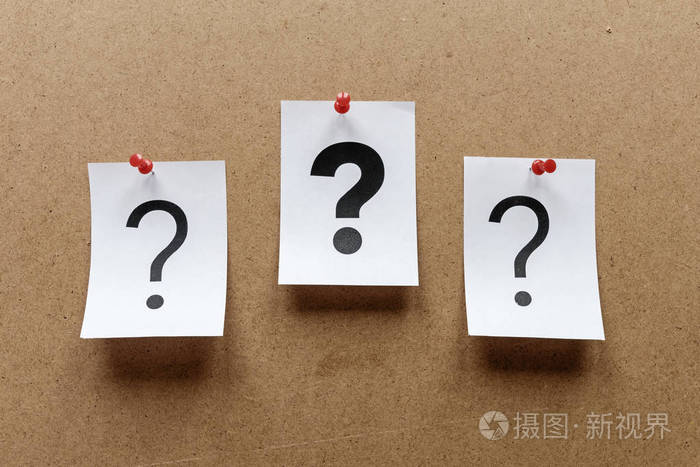 三个问号钉在木制告示板上,中间有一个粗体印在白纸上
