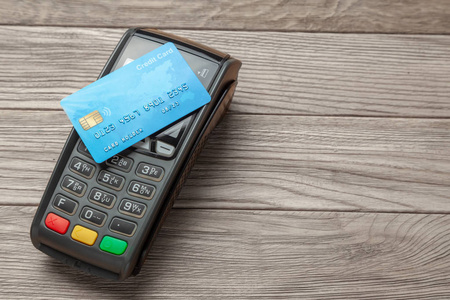 木制背景上的POS终端支付机信用卡。 非接触式付款。 NFC技术