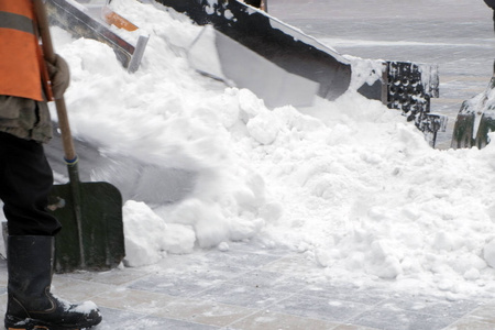 挖掘机清理城市里大量雪的街道。 工作铲子耙雪。 冬天。 暴风雪后的清洁。 市政城市道路维护。