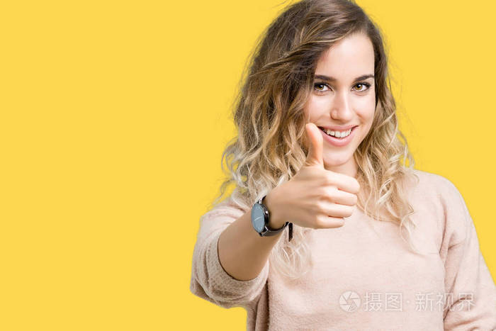 美丽的年轻金发女人穿着毛衣,穿着汗衫,在孤立的背景下,用手做快乐的