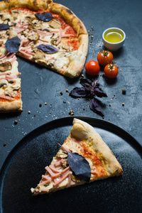 一块新烤的意大利披萨放在黑色盘子上。 深色背景侧视图