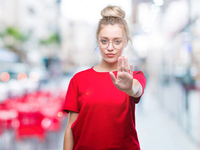 年轻的金发女人戴着眼镜在孤立的背景上做停止用手掌唱歌。 警告表情，脸上有负面和严肃的手势。