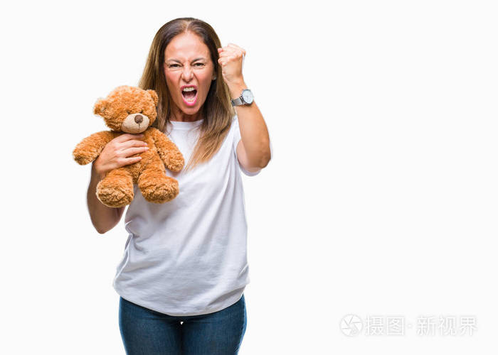 中年西班牙裔妇女抱着可爱的泰迪熊毛绒在孤立的背景上愤怒疯狂和沮丧