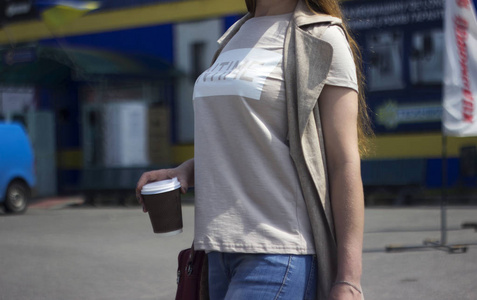 时尚的金发女郎拿着一个带有咖啡背景的纸杯