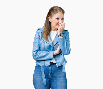 美丽的中年成熟的女人穿着时尚的皮夹克，在孤立的背景上看起来压力和紧张，双手咬着嘴的指甲。 焦虑问题。