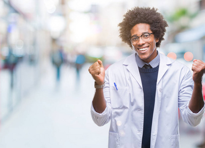 美国黑人医生科学家男子在孤立的背景下庆祝惊讶和惊讶的成功，举起手臂和睁开眼睛。赢家概念。