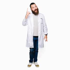 年轻的金发科学家，穿着白色外套，用手指指点着成功的想法。离开而快乐。一号。