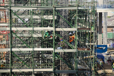 亚洲人民和泰国工人与重型机械工人建造新的建筑工地高层建筑在脚手架在首都曼谷，泰国。
