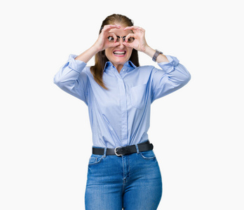 漂亮的中年成熟的商务女性戴着眼镜，在孤立的背景上做着好的手势，就像双筒望远镜伸出舌头，透过手指看着眼睛。 疯狂的表情。