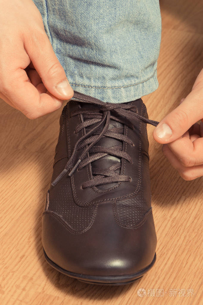 双手系棕色舒适皮鞋鞋带