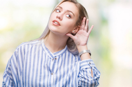 年轻的金发女人在孤立的背景上微笑，用手捂住耳朵听谣言或流言蜚语。 耳聋概念。