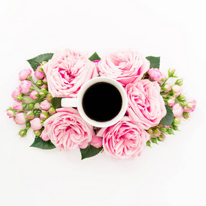 白色背景上带有黑色咖啡饮料杯的粉红色花朵。 平躺顶部视图。 花的质地。
