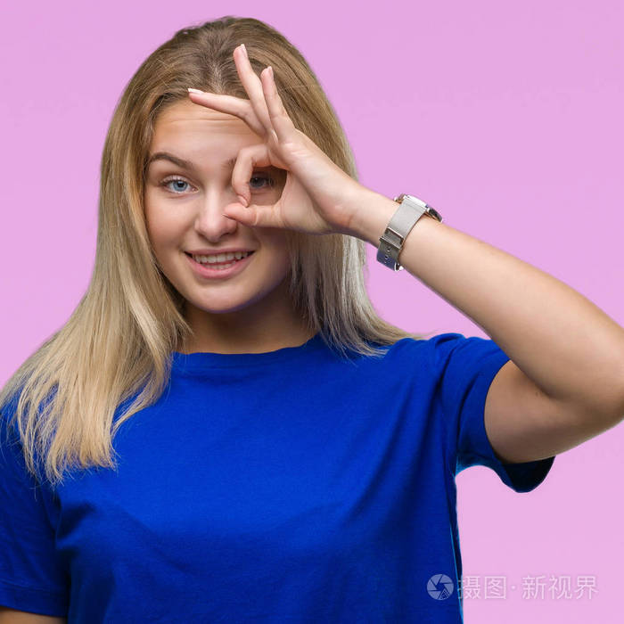 年轻的白种人女人在孤立的背景下做ok手势,用手微笑的眼睛看着手指,用