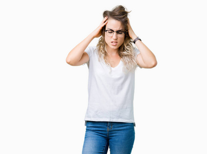 美丽的年轻金发女人戴着眼镜在孤立的背景上，手在头上疼痛，因为压力。 偏头痛。