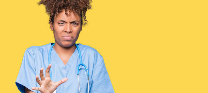 年轻的非裔美国医生女人在孤立的背景下厌恶的表情，不高兴和恐惧的做厌恶的脸，因为厌恶的反应。 举起双手。 令人讨厌的概念。