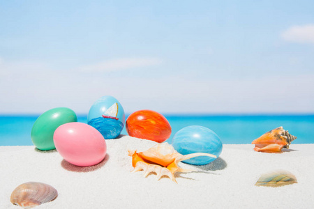 复活节在热带海滩背景。 白沙上的鸡蛋。 春季假期及旅游概念