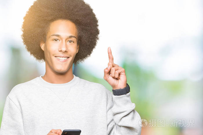 年轻的非裔美国人，一头非洲发，使用智能手机，惊讶于一个想法或问题，指着一个快乐的脸第一