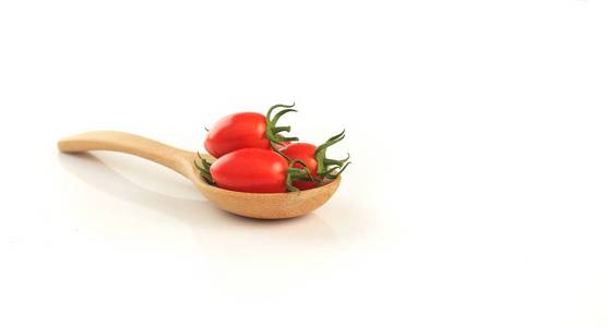 新鲜的红番茄放在木勺上，白色背景