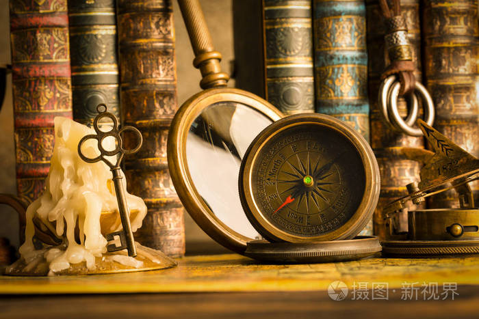 古董指南针在蜡烛的背景上,有钥匙和书. 复古风格.