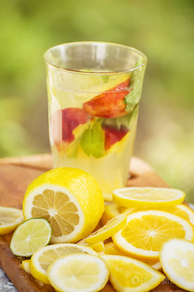 水果橙柠檬水在玻璃杯和各种柑橘水果的自然背景在花园里
