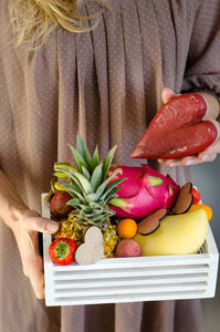 s hands holding a wooden box with exotic fruits. Romantic gift. 