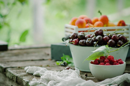 混合新鲜浆果和水果在老式木箱在乡村木制背景。生的健康食品。各种夏季浆果和水果。