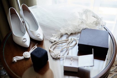 豪华白色女鞋，面纱，金色结婚戒指和新娘首饰珍珠项链，手镯和耳环在木桌上，复制空间。为婚礼做准备。新娘配件