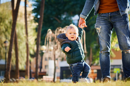 s hand when walking in the park on a sunny day. Father and son r