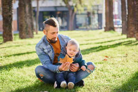 阳光明媚的一天，小胡子男和他可爱的小儿子在公园里玩。 一对父子。