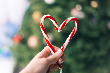 一只手在背景上的心形糖果棒照片